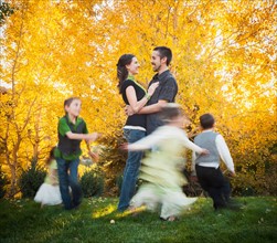 Bountiful, Family with children (2-3, 4-5, 6-7, 8-9) dancing in garden at autumn. Photo: Mike Kemp