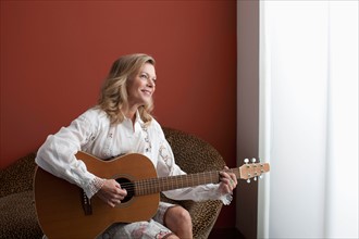 Portrait of mature woman playing guitar. Photo: Dan Bannister
