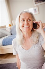 Senior woman talking on phone with husband lying on bed. Photo: Rob Lewine