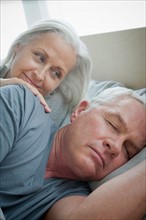 Senior woman looking at sleeping husband. Photo : Rob Lewine
