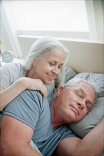 Portrait of senior couple laying in bed in morning. Photo : Rob Lewine