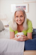 Portrait of cheerful senior woman holding coffee cup. Photo: Rob Lewine