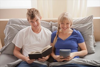 Portrait of couple sitting in bed reading. Photo : Rob Lewine