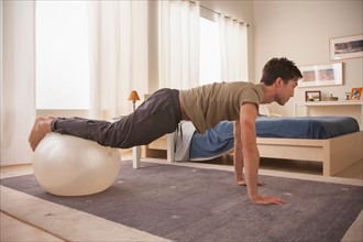 Man doing yoga using fitness ball. Photo : Rob Lewine