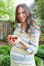 Portrait of pregnant mid adult woman holding strawberries. Photo : Jessica Peterson
