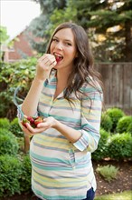 Portrait of pregnant mid adult woman eating strawberries. Photo : Jessica Peterson