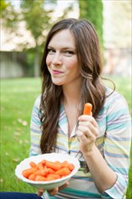 Portrait of mid adult woman eating carrots. Photo : Jessica Peterson