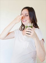Portrait of pregnant mid adult woman drinking green juice. Photo: Jessica Peterson