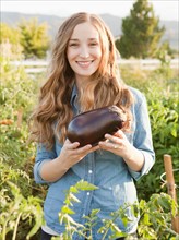 Portrait of young woman holding eggplant. Photo : Jessica Peterson