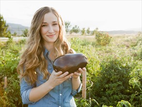 Portrait of young woman holding eggplant. Photo: Jessica Peterson
