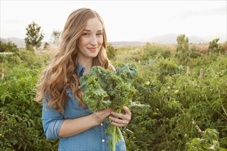 Portrait of young woman holding kale. Photo : Jessica Peterson