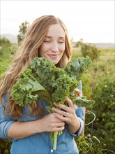 Portrait of young woman holding kale. Photo: Jessica Peterson