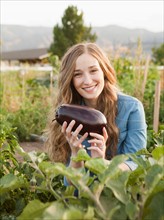 Portrait of young woman harvesting eggplant. Photo: Jessica Peterson