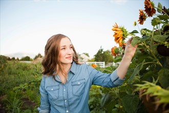 Portrait of young woman harvesting sunflowers. Photo : Jessica Peterson