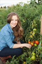 Portrait of young woman harvesting tomatoes. Photo: Jessica Peterson