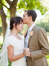 Groom kissing bride in park. Photo : Jessica Peterson