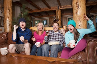 Friends watching tv in log cabin. Photo: Jessica Peterson
