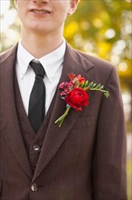 Mid section of groom wearing full suit decorated with boutonniere. Photo: Jessica Peterson