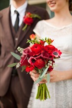 Mid section of wedding couple with bouquet in focus. Photo : Jessica Peterson