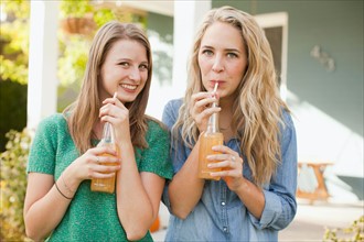 Portrait of two friends drinking soda through straw. Photo: Jessica Peterson