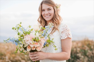 Portrait of bride holding bunch of flowers. Photo : Jessica Peterson