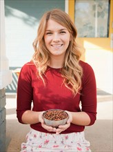 Portrait of young woman holding bowl with pine nuts. Photo : Jessica Peterson