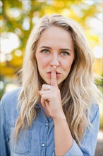 Front view portrait of young woman with finger on lips. Photo : Jessica Peterson
