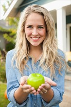 Portrait of young woman holding green apple. Photo: Jessica Peterson