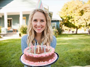 Portrait of young woman holding birthday cake. Photo : Jessica Peterson