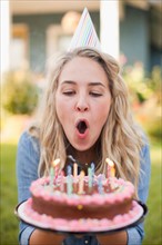 Portrait of young woman blowing birthday candles. Photo : Jessica Peterson