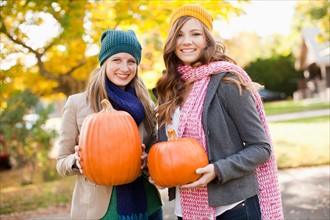 Portrait of two young women holding pumpkins. Photo : Jessica Peterson