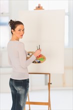 Woman painting at easel.