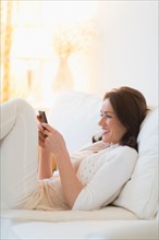 Woman sitting on sofa and texting.