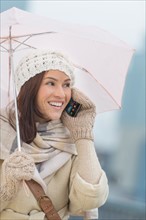 Woman with umbrella using phone.