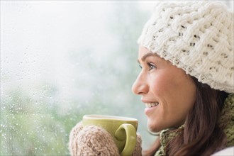 Woman in warm clothes holding mug.