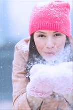 Portrait of woman blowing snow from hands.