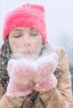 Portrait of woman blowing snow from hands.