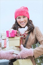 Portrait of woman in winter clothes carrying presents.