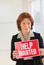 Portrait of businesswoman holding help wanted sign.