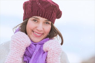 Portrait of young woman wearing knit hat, gloves and scarf.