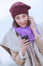 Young woman in wearing warm clothes and using mobile phone.