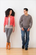 Smiling couple standing against white wall.