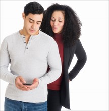 Studio shot of young couple looking at cell phone.