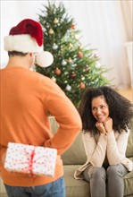 Man holding Christmas gift for woman.