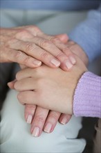 Close-up of hands of grandmother and granddaughter (16-17).