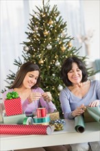 Grandmother and granddaughter (16-17) wrapping christmas gifts.