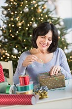Senior woman wrapping christmas gifts.