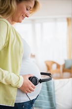 Pregnant woman with headphones on belly