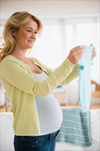 Pregnant woman with baby clothes