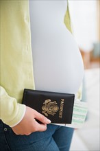 Pregnant woman holding passport and flight tickets